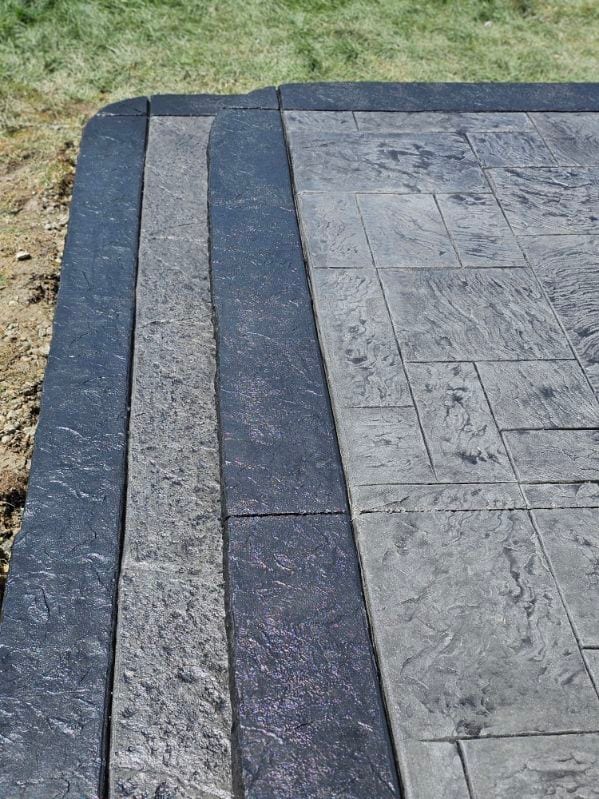 Charcoal stamped patio with a banded border by General Maintenance Works