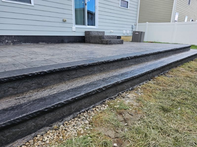 Stamped patio and steps running along the house by General Maintenance Works